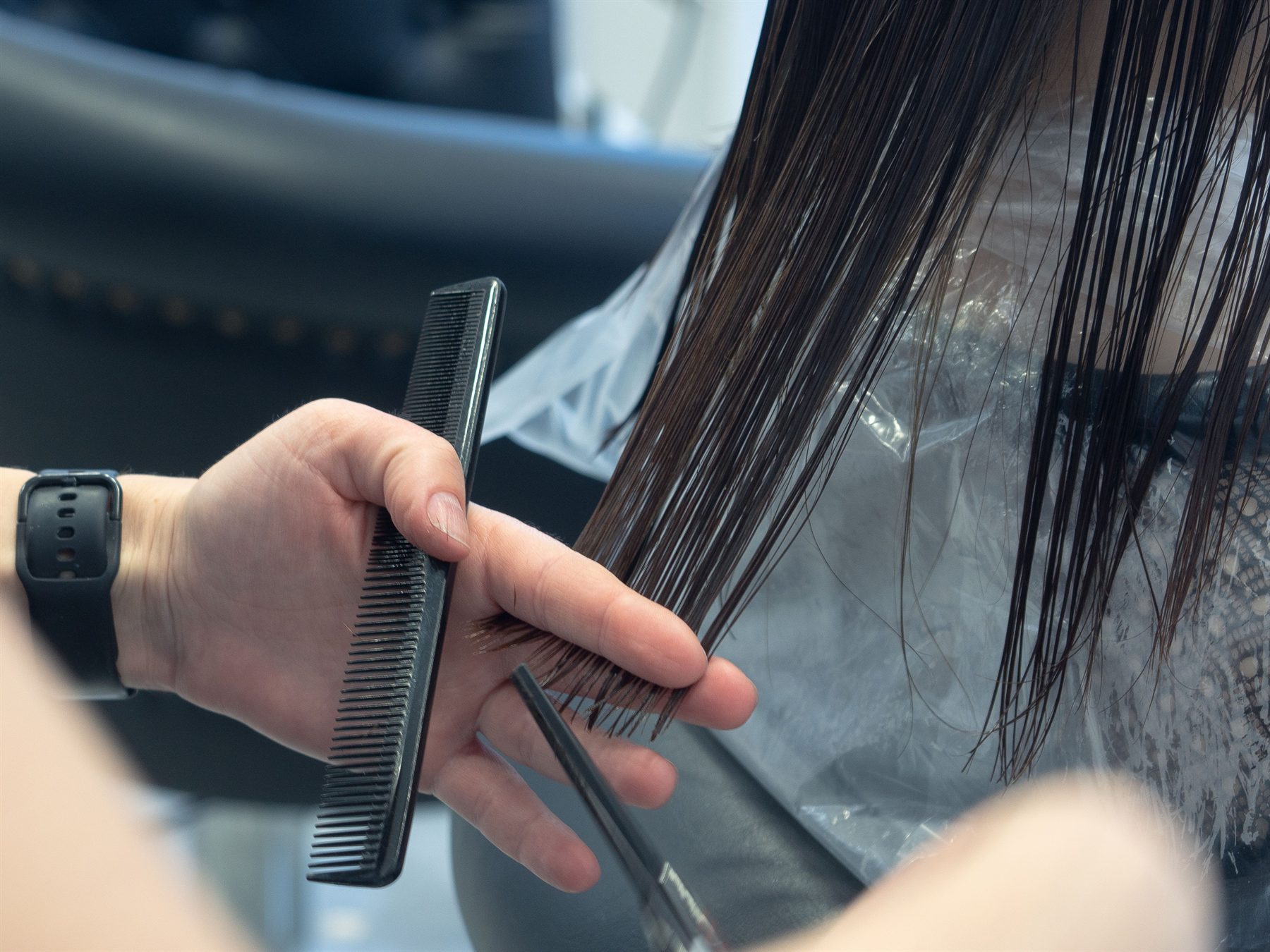 A stylist combing through a new client's hair