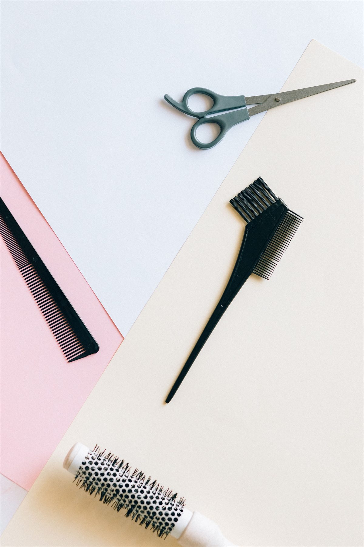 Salon scissors, combs and a brush arranged on blush and cream paper